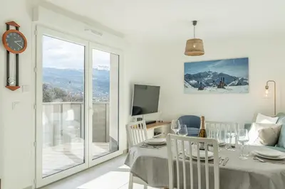 a white dining room with a table and a tv at Apartment Le Valleen in Saint-Gervais-les-Bains