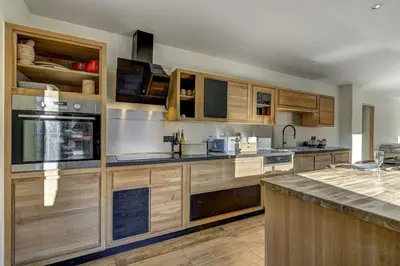 a large kitchen with wooden cabinets and a counter at Lac - Cosy 120m2 Vues MtBlanc Flegere 5mn Lac Golf in Chamonix-Mont-Blanc