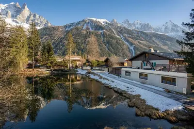a house and a river with a mountain in the background at Lac - Cosy 120m2 Vues MtBlanc Flegere 5mn Lac Golf in Chamonix-Mont-Blanc