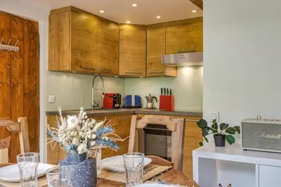 a kitchen with wooden cabinets and a table with flowers at Yagire - Charmant Mazot 4pax HomeCine Nature Terrasse in Chamonix-Mont-Blanc