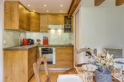 a kitchen with wooden cabinets and a table with chairs at Yagire - Charmant Mazot 4pax HomeCine Nature Terrasse in Chamonix-Mont-Blanc