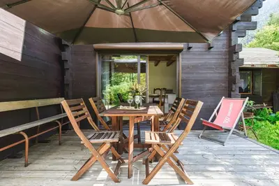 a wooden table with chairs and an umbrella on a patio at Yagire - Charmant Mazot 4pax HomeCine Nature Terrasse in Chamonix-Mont-Blanc