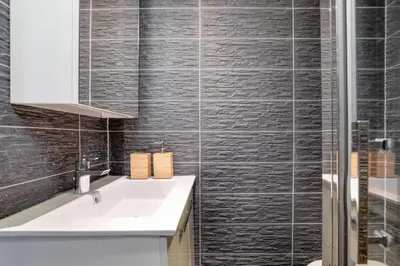 a bathroom with a white sink and black tiles at Yagire - Charmant Mazot 4pax HomeCine Nature Terrasse in Chamonix-Mont-Blanc