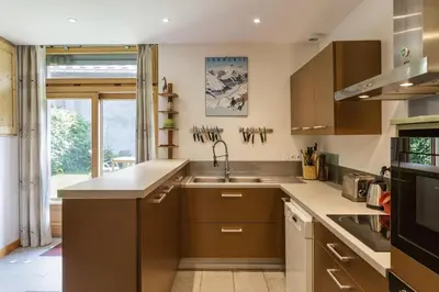 a kitchen with brown cabinets and a sink at Ferme d Aristide - Chalet 160m2 Calme Sauna Vue Bus Train 250m in Chamonix-Mont-Blanc