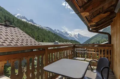 a balcony with a table and a view of mountains at Ferme d Aristide - Chalet 160m2 Calme Sauna Vue Bus Train 250m in Chamonix-Mont-Blanc