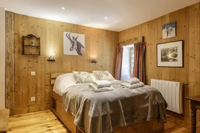 a bedroom with wooden walls and a bed with towels on it at Ferme d Aristide - Chalet 160m2 Calme Sauna Vue Bus Train 250m in Chamonix-Mont-Blanc