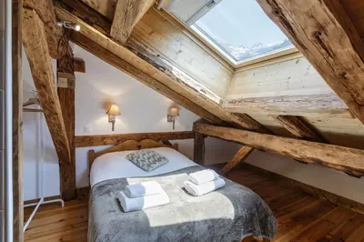 a attic bedroom with a bed and a skylight at Ferme d Aristide - Chalet 160m2 Calme Sauna Vue Bus Train 250m in Chamonix-Mont-Blanc