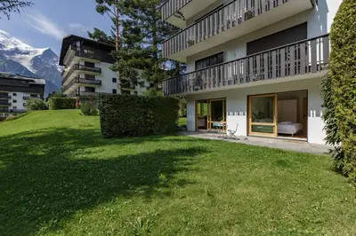 a house with a green yard in front of a building at KV - Moderne 2CH Vue MtBlanc Terrasse Brevent 3mn in Chamonix-Mont-Blanc