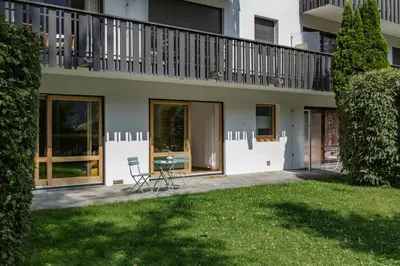 a house with a balcony and a table in the yard at KV - Moderne 2CH Vue MtBlanc Terrasse Brevent 3mn in Chamonix-Mont-Blanc