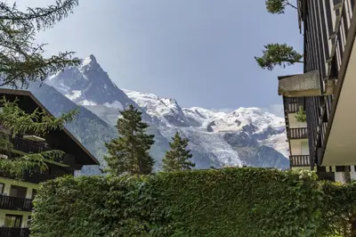 a view of a snow covered mountain from between buildings at KV - Moderne 2CH Vue MtBlanc Terrasse Brevent 3mn in Chamonix-Mont-Blanc