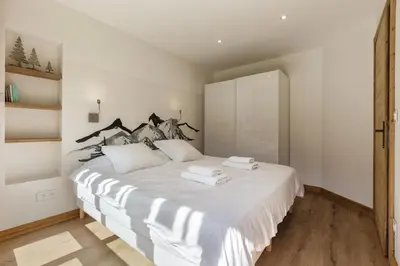 a bedroom with a white bed with towels on it at KV - Moderne 2CH Vue MtBlanc Terrasse Brevent 3mn in Chamonix-Mont-Blanc