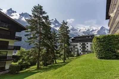 a street with trees and mountains in the background at KV - Moderne 2CH Vue MtBlanc Terrasse Brevent 3mn in Chamonix-Mont-Blanc