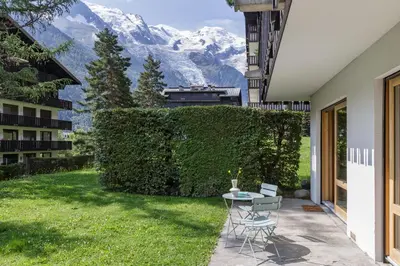 a garden with a table and chairs on a patio at KV - Moderne 2CH Vue MtBlanc Terrasse Brevent 3mn in Chamonix-Mont-Blanc