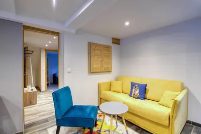 a living room with a yellow couch and blue chairs at Lou Dava Chic Apt Near Centre Chamonix - Happy Rentals in Chamonix-Mont-Blanc
