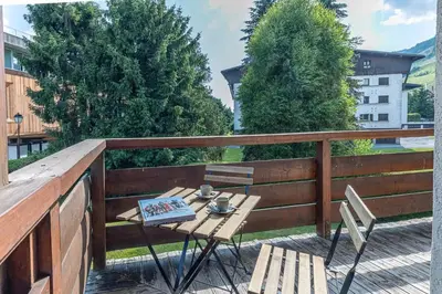 a table and chairs on a balcony with trees at Lara Megeve Jaillet proche du village Parking in Megève