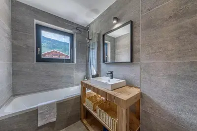 a bathroom with a sink and a mirror and a tub at Lara Megeve Jaillet proche du village Parking in Megève