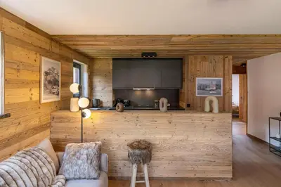 a living room with a couch and a kitchen at Lara Megeve Jaillet proche du village Parking in Megève