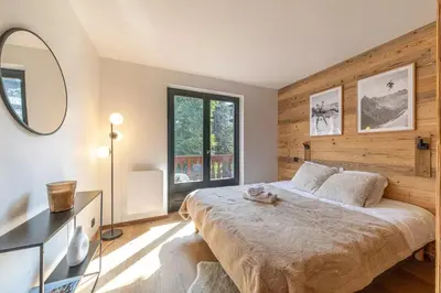 a bedroom with a large bed and a mirror at Lara Megeve Jaillet proche du village Parking in Megève