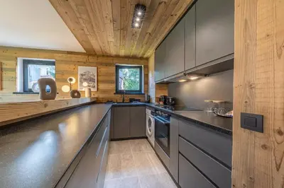 a kitchen with black countertops and a wooden ceiling at Lara Megeve Jaillet proche du village Parking in Megève