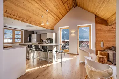 a kitchen and living room with wooden ceilings at Toits des Pècles Top-Floor Alpine Apartment with Stunning Mont-Blanc View in Chamonix-Mont-Blanc