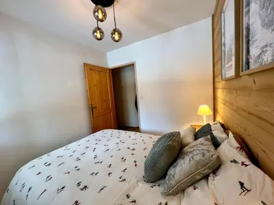 a bedroom with a large bed with a wooden wall at Appartement familial à Samoëns avec piscine et parking - FR-1-624-189 in Samoëns