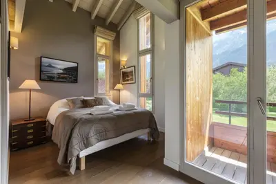 a bedroom with a bed and a large window at Meleze - Chalet 5CH Vues Jardin Lac Remontees 200m in Les Houches