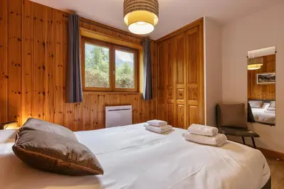 a bedroom with a large bed with two towels on it at Arve - Chalet 4CH Jardin Nature Vues BBQ Poele in Chamonix-Mont-Blanc