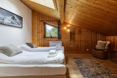two beds in a room with wooden walls at Arve - Chalet 4CH Jardin Nature Vues BBQ Poele in Chamonix-Mont-Blanc