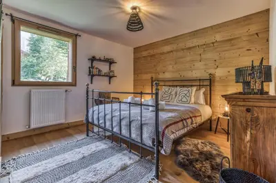 a bedroom with a bed and a wooden wall at Turra - Cosy 80m2 Central Remontee Parking Calme in Les Houches