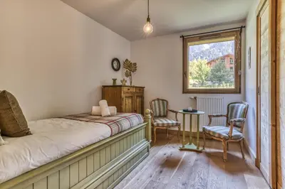 a bedroom with a bed and two chairs and a window at Turra - Cosy 80m2 Central Remontee Parking Calme in Les Houches