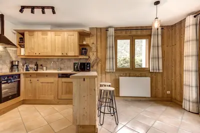 a kitchen with wooden cabinets and a counter top at Mouilles - Apart 113m2 Jardin Calme Garage Bar Centre in Chamonix-Mont-Blanc