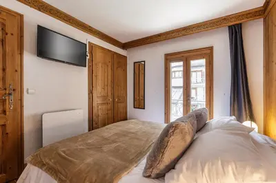 a bedroom with a bed and a tv on the wall at Cristal - Duplex Sauna Parking Remontee 300m Balcons in Chamonix-Mont-Blanc