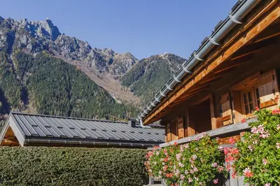 a building with mountains in the background with flowers at Barrats Vert - Mazot Hypercentre 1km Nature Vues Calme in Chamonix-Mont-Blanc