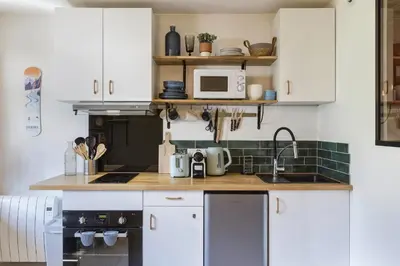 a kitchen with white cabinets and a sink at Petit Balcon - Cosy 1CH Remontees 500m Vue Parking Calme in Les Houches