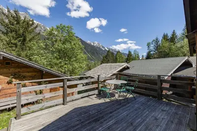 a deck with a table and chairs on it at Baribal - Charmant Mazot Terrasse Nature Vue Parking in Chamonix-Mont-Blanc