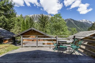 a wooden deck with a table and chairs on it at Baribal - Charmant Mazot Terrasse Nature Vue Parking in Chamonix-Mont-Blanc