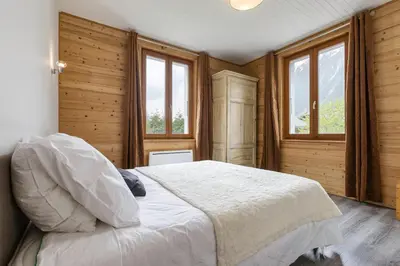 a bedroom with a bed with wooden walls and windows at Epicea - Cosy 1CH 35m2 Centre Parking Calme WIFI in Chamonix-Mont-Blanc