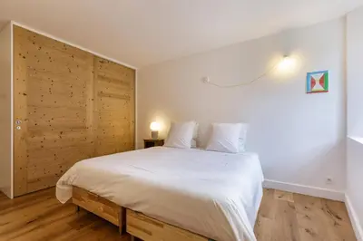 a bedroom with a white bed with a wooden wall at Cinema - Lumineux Moderne 2CH 100m2 Hypercentre Vues in Chamonix-Mont-Blanc