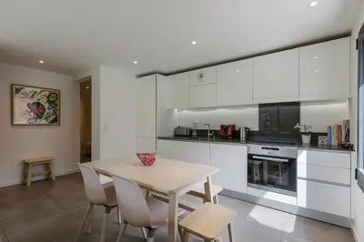 a kitchen with white cabinets and a table and chairs at Cordee - Appart 2CH Balcon SUD Vues Residence Premium in Chamonix-Mont-Blanc