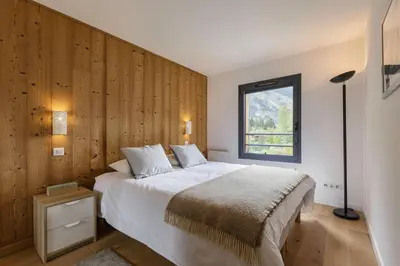 a bedroom with a large bed with a wooden wall at Cordee - Appart 2CH Balcon SUD Vues Residence Premium in Chamonix-Mont-Blanc