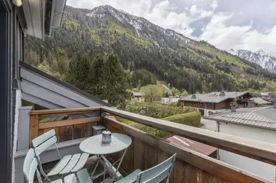 a balcony with a table and chairs and mountains at Flocon - Loft Moderne 8pax Sauna Poele Vues Garage in Chamonix-Mont-Blanc
