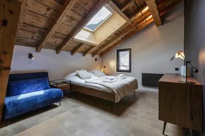 a bedroom with a bed and a blue couch at Flocon - Loft Moderne 8pax Sauna Poele Vues Garage in Chamonix-Mont-Blanc