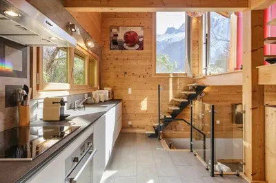 a kitchen with a staircase in a wooden house at Gaillands Mazot Lumineux 55m2 Vues Confort in Chamonix-Mont-Blanc