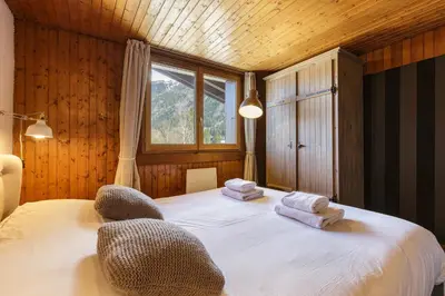 a bedroom with a bed with two chairs and a window at Refuge Scandinave - Duplex 80m2 Vue Garage Calme 200m TrainBus in Chamonix-Mont-Blanc