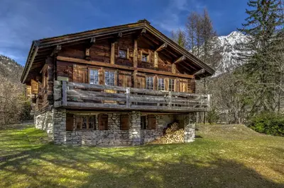 a large log house on a grassy field at Frasserands - Chalet 155m2 Vue 360 Calme Bus Train 150m in Chamonix-Mont-Blanc