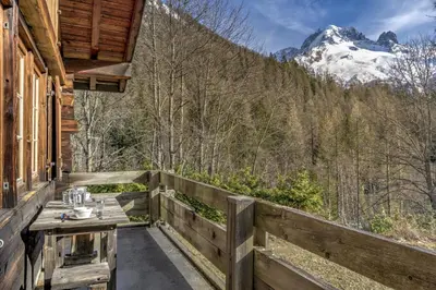 a table on the porch of a cabin with a mountain at Frasserands - Chalet 155m2 Vue 360 Calme Bus Train 150m in Chamonix-Mont-Blanc