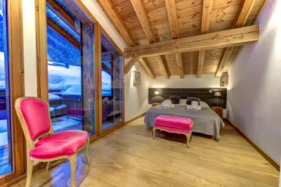 a bedroom with a bed and two pink chairs at Chosalets - Chalet 200m2 Cheminee Jacuzzi Sauna Vues in Chamonix-Mont-Blanc
