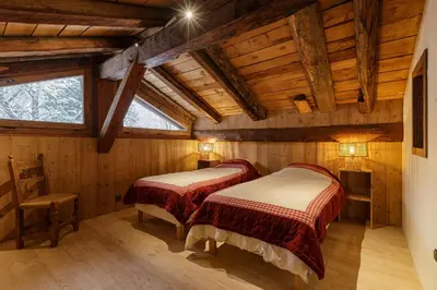 two beds in a room with wooden walls at Lavancher - Chalet 400m2 Ferme 1803 renovee Sauna Billard in Chamonix-Mont-Blanc