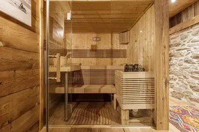 a sauna with wooden walls and a glass door at Lavancher - Chalet 400m2 Ferme 1803 renovee Sauna Billard in Chamonix-Mont-Blanc