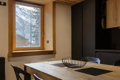 a dining room with a wooden table and a window at Vouvy - Moderne 4pax Remontee Flegere 5min Praz Arve in Chamonix-Mont-Blanc